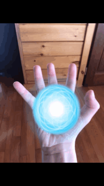 a person 's hand is holding a blue sphere in it