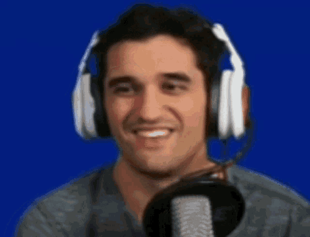 a man wearing headphones is smiling in front of a blue background .