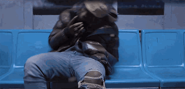 a man is sitting on a blue bench with his arm around another man