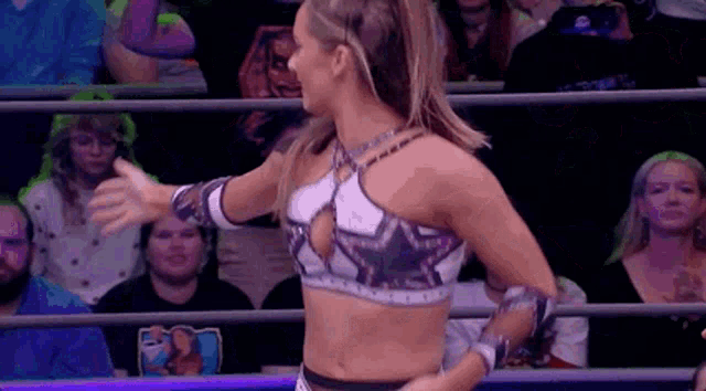 a woman is standing in a wrestling ring with her hands outstretched .