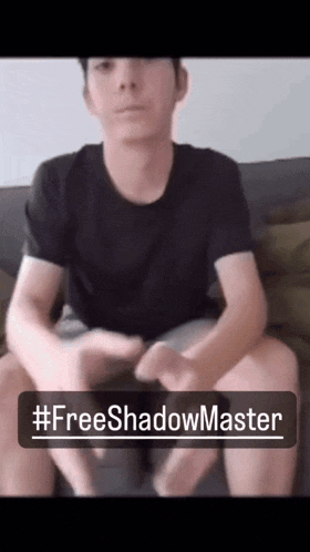 a man sitting on a couch with a sign that says #freeshadowmaster on it