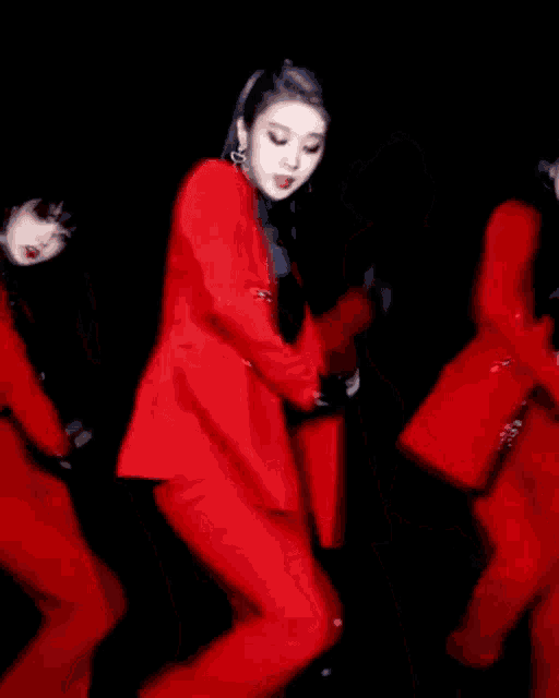 a group of people in red suits are dancing on a stage in a dark room .