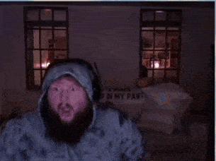 a man with a beard is wearing headphones and a hoodie in a room .
