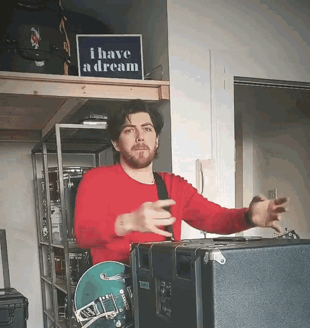 a man in a red sweater stands in front of a sign that says i have a dream