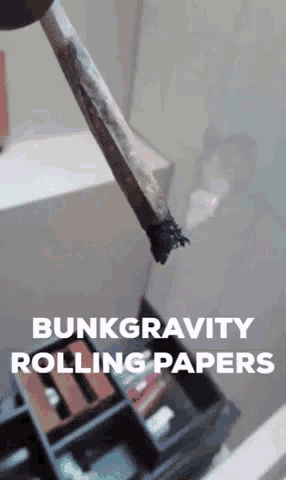 a person is holding a rolled up cigarette with the words bunkgravity rolling papers written below it