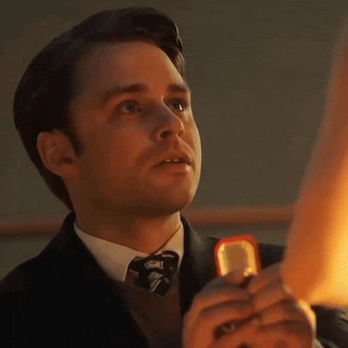 a man in a suit and tie is holding a ring in his hand