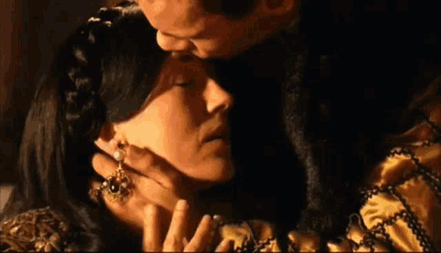a man is kissing a woman on the forehead while she is wearing earrings