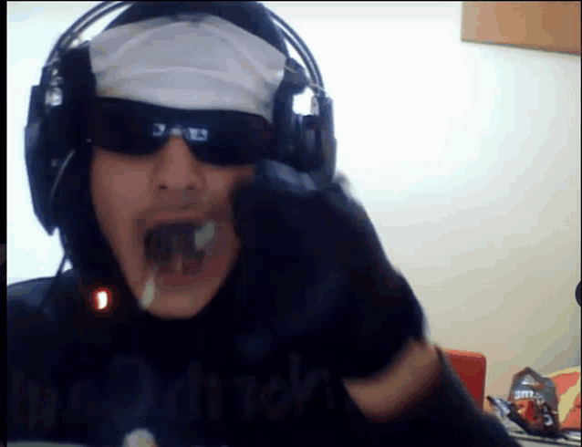 a man wearing headphones and sunglasses is eating a candy bar