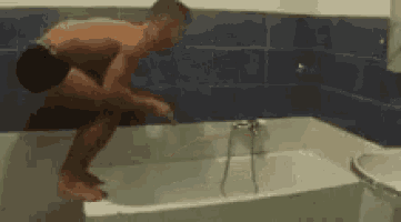 a man without a shirt is kneeling in a bathtub