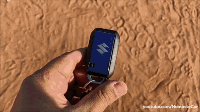 a person is holding a suzuki car key