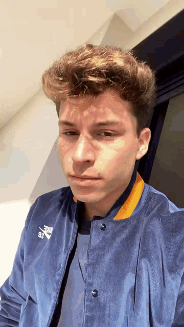 a young man in a blue nike jacket looks at the camera