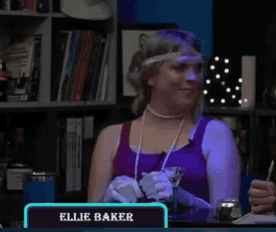 a woman in a purple tank top sits at a table with a sign that says ellie baker