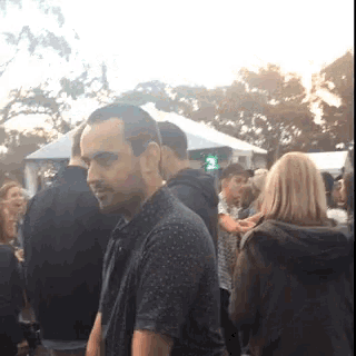 a man is standing in a crowd of people with a green light in the background