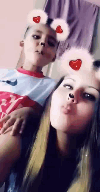 a girl and a boy are posing for a picture with hearts on their faces .