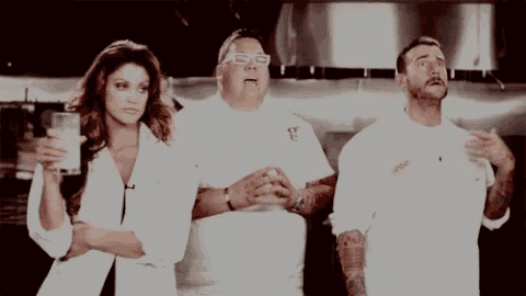 a woman holding a glass of milk stands between two men in white shirts