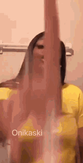a woman in a yellow shirt is making a funny face while giving the middle finger .