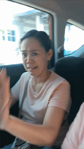 a woman in a pink shirt is sitting in a car