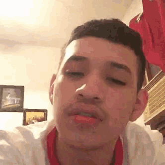 a young man is making a funny face while looking at the camera in a room .