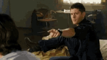 a man is sitting on a bed stretching his leg