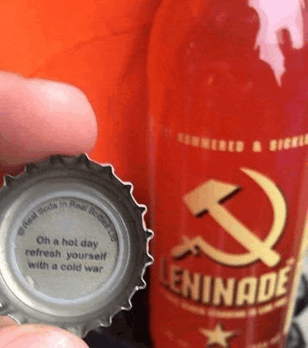 a person is holding a bottle cap next to a bottle of leninade soda