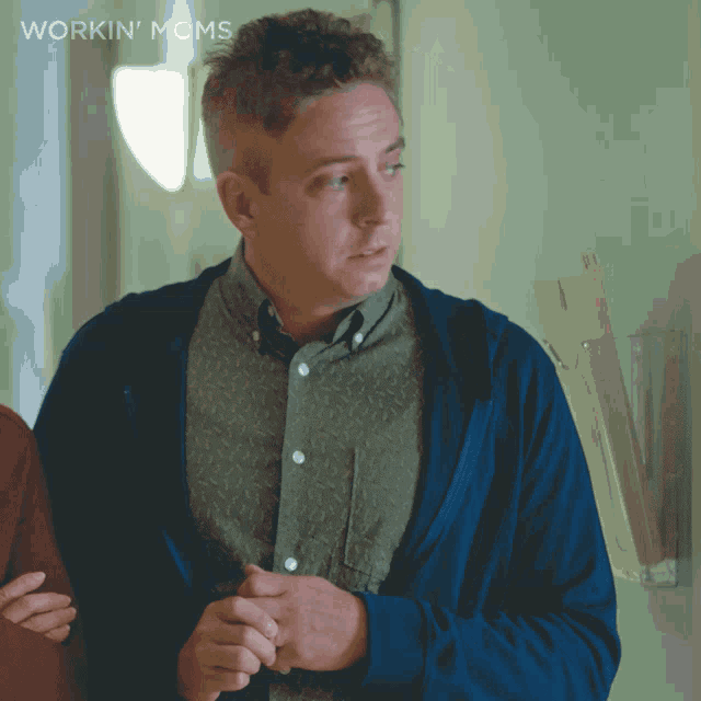 a man in a blue jacket is standing in front of a wall that says workin ' moms on it