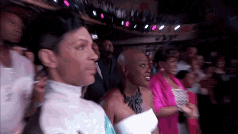 a man and a woman are standing in a crowd watching a performance