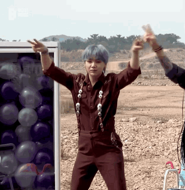 a young man with blue hair is dancing in front of balloons and a sign that says ' billboard music '