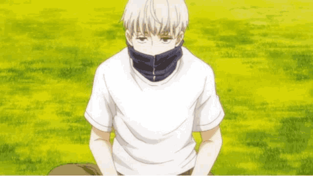 a young man wearing a white shirt and a blue scarf around his neck is sitting in the grass .