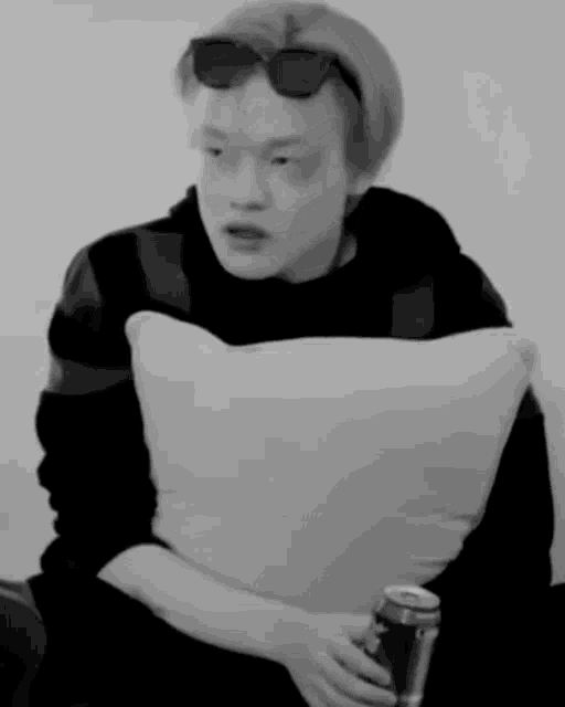 a man is sitting on a couch holding a can of soda .