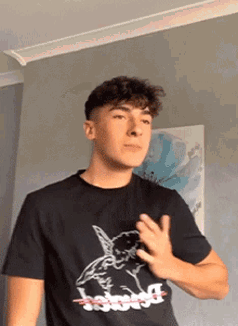 a young man wearing a black t-shirt with a picture of an angel on it is standing in a room