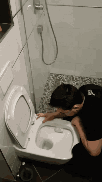 a man is vomiting into a toilet with the lid open