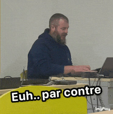 a man with a beard sits at a desk with a laptop and the words " euh par contre " above him