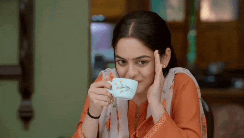 a woman is drinking from a blue cup with flowers on it