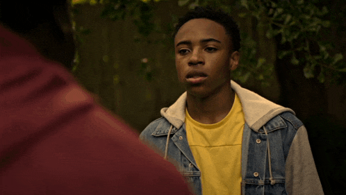 a young man wearing a denim jacket and a yellow t-shirt