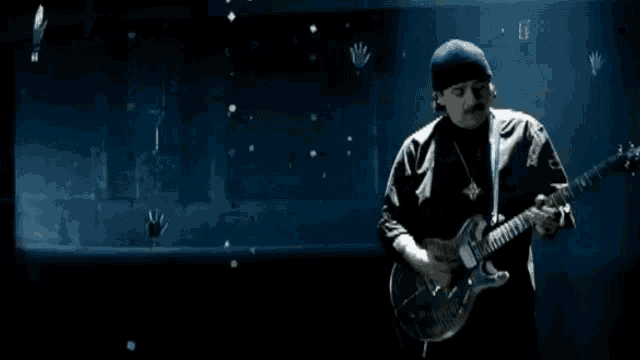 a man is playing a guitar in the dark