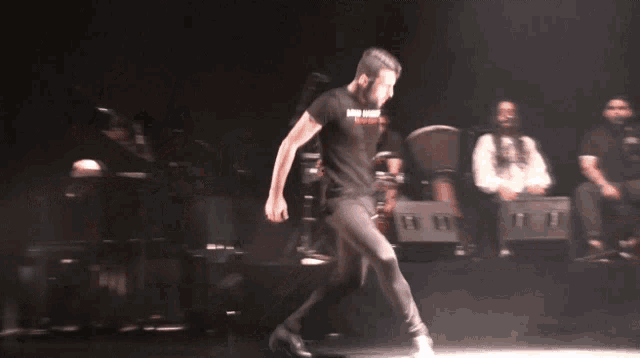 a man in a black shirt is dancing in front of a crowd of people