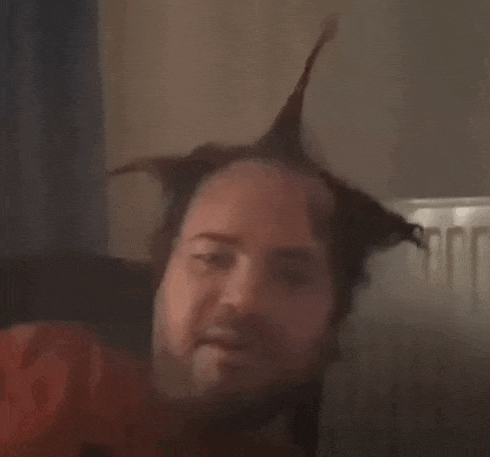 a man with a beard and a mohawk is looking at the camera .