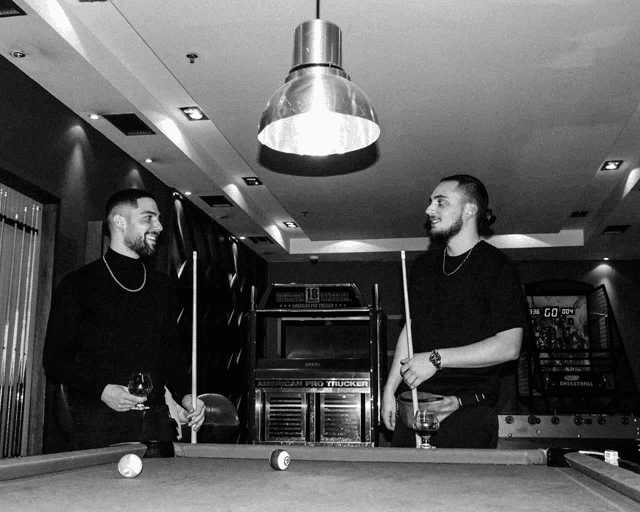 two men playing pool in front of an american pro trucker