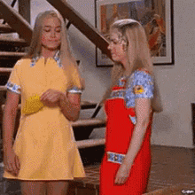 two women are standing next to each other in a living room .