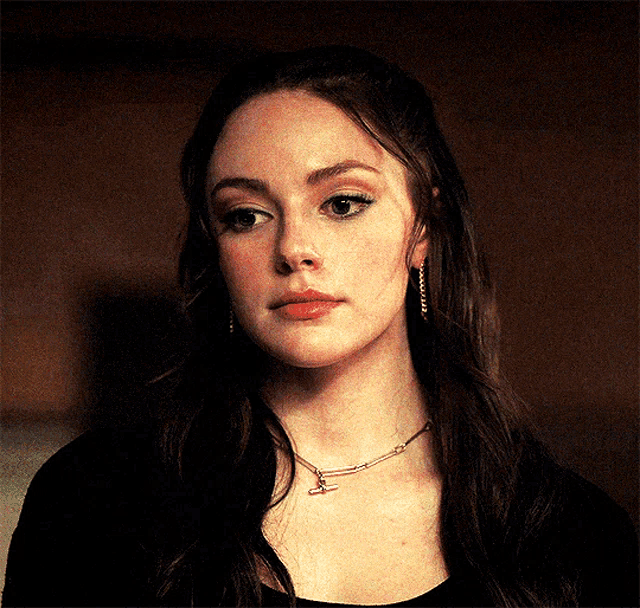 a woman wearing a necklace and earrings is looking at the camera .
