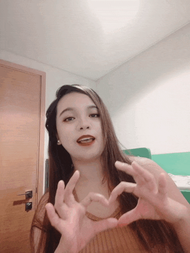 a woman making a heart with her hands in front of a door