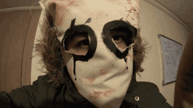 a person wearing a white mask with a black circle with the letter p on it