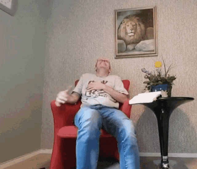 a man is sitting in a chair with a picture of a lion above him