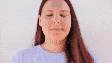 a woman with long red hair is wearing a white shirt and making a funny face .
