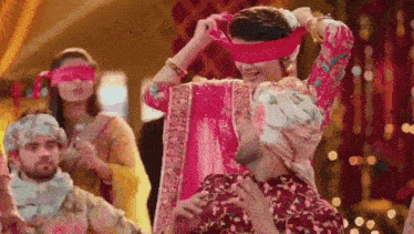 a woman in a pink dress is dancing with a man in a turban .