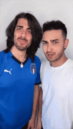 two men standing next to each other with one wearing a blue puma shirt