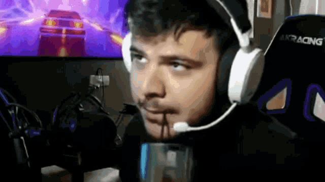 a man wearing headphones and a microphone is sitting in front of a computer .