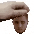 a hand is holding a man 's head in its palm .