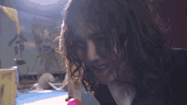 a close up of a person 's face with a pink ball in the background