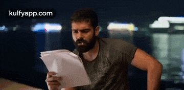 a man with a beard is looking at a piece of paper .